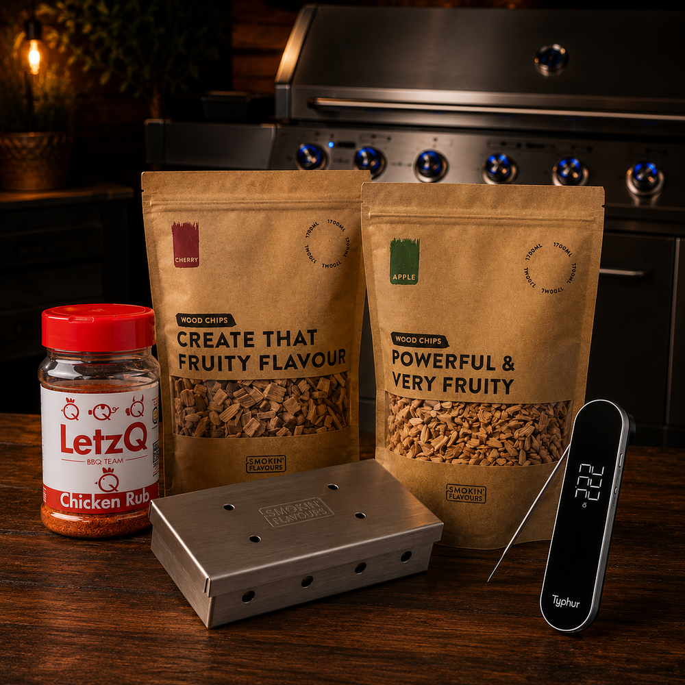 Kipsaté Gas Experience Bundle met Typhur InstaProbe Core, LetzQ Chicken Rub, Smokin' Flavours appel- en kersenrooksnippers en RVS smokerbox op een houten tafel met gasbarbecue op de achtergrond.