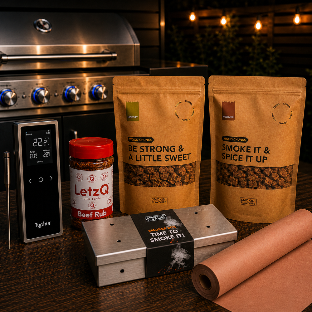 Ultimate Brisket Gas Experience Bundle met Typhur Sync One, LetzQ Beef Rub, Smokin' Flavours hickory- en mesquite rookchunks, RVS smokerbox en Pink Butcher Paper op een houten tafel met gasbarbecue op de achtergrond.