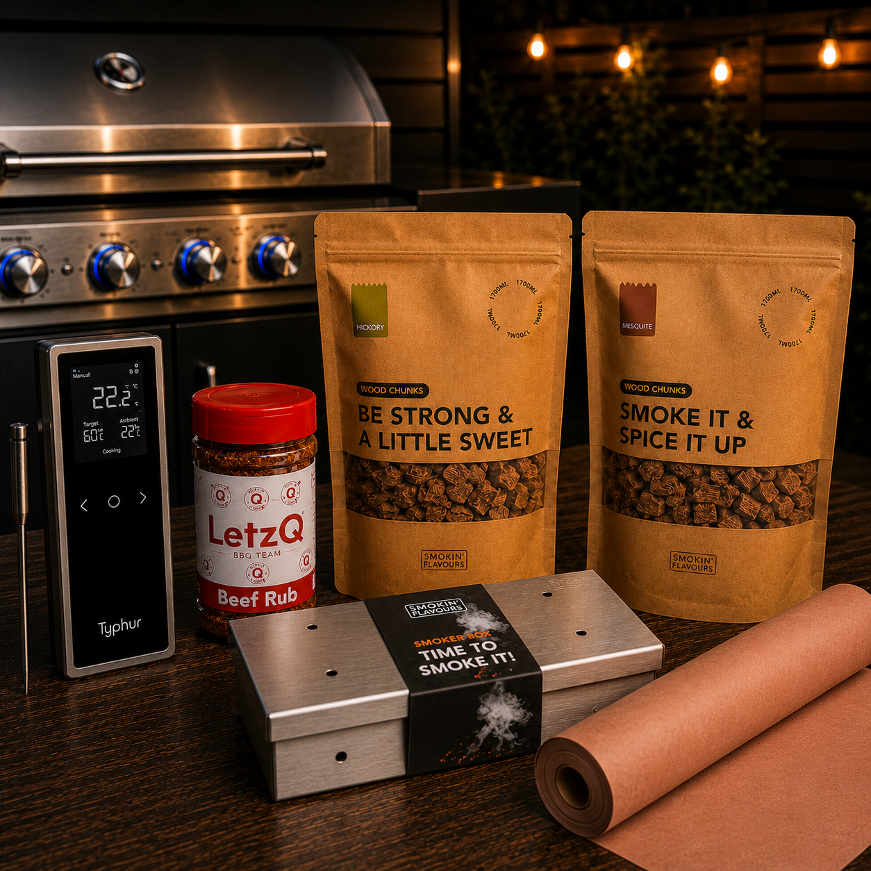 Ultimate Brisket Gas Experience Bundle met Typhur Sync One, LetzQ Beef Rub, Smokin' Flavours hickory- en mesquite rookchunks, RVS smokerbox en Pink Butcher Paper op een houten tafel met gasbarbecue op de achtergrond.